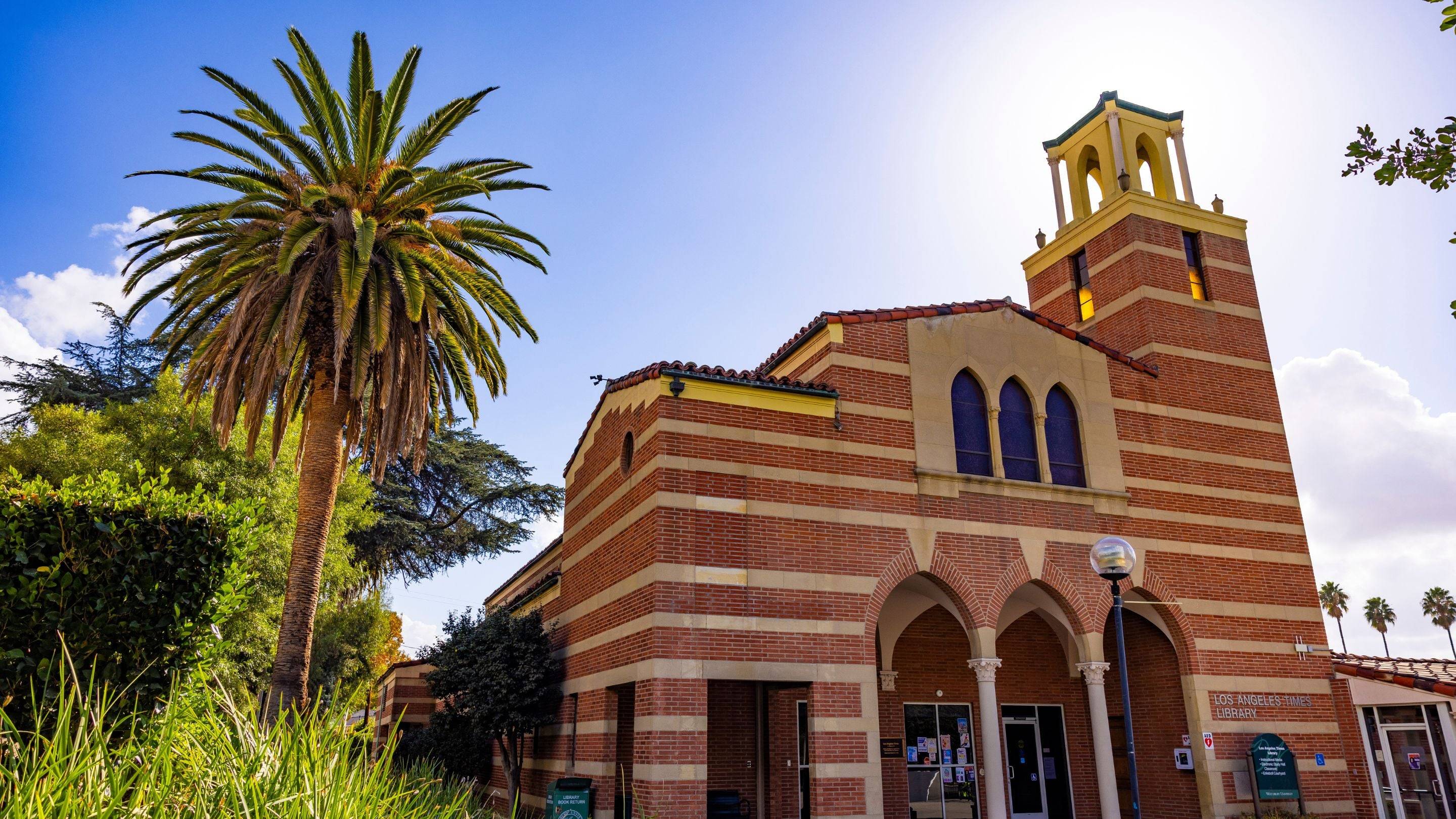 a building with a bell tower and palm tree