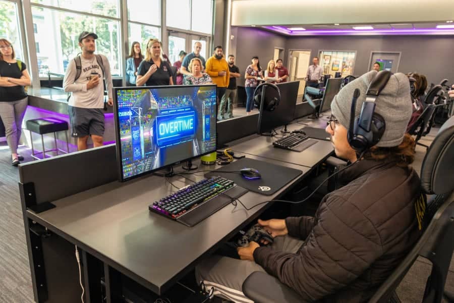 a man sitting at a desk with a computer and a group of people