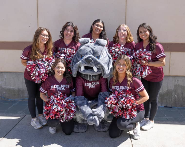 a group of cheerleaders posing with a mascot