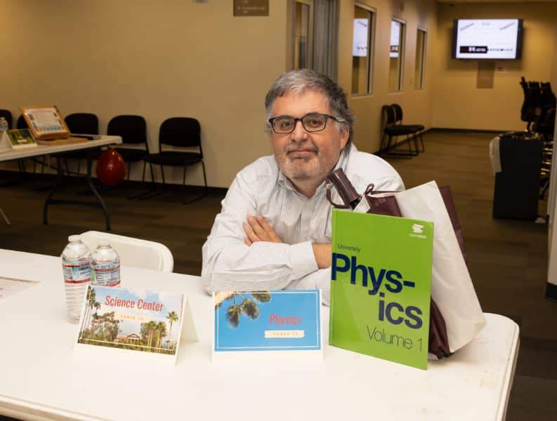 a man sitting at a table with books and a bag