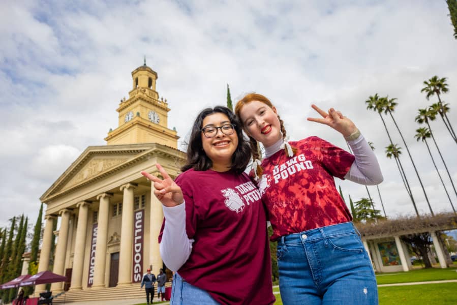 two women posing for a picture in front of a building