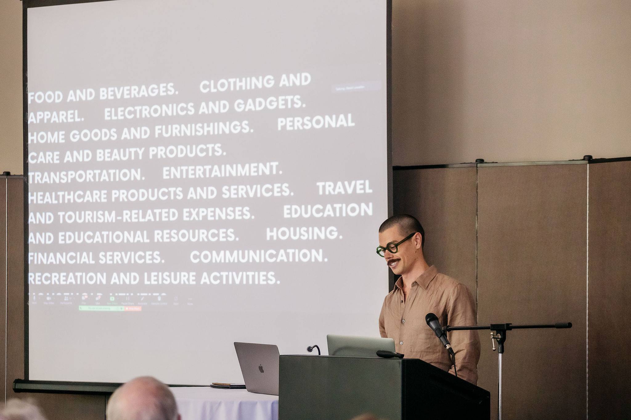a man standing at a podium with a screen behind him