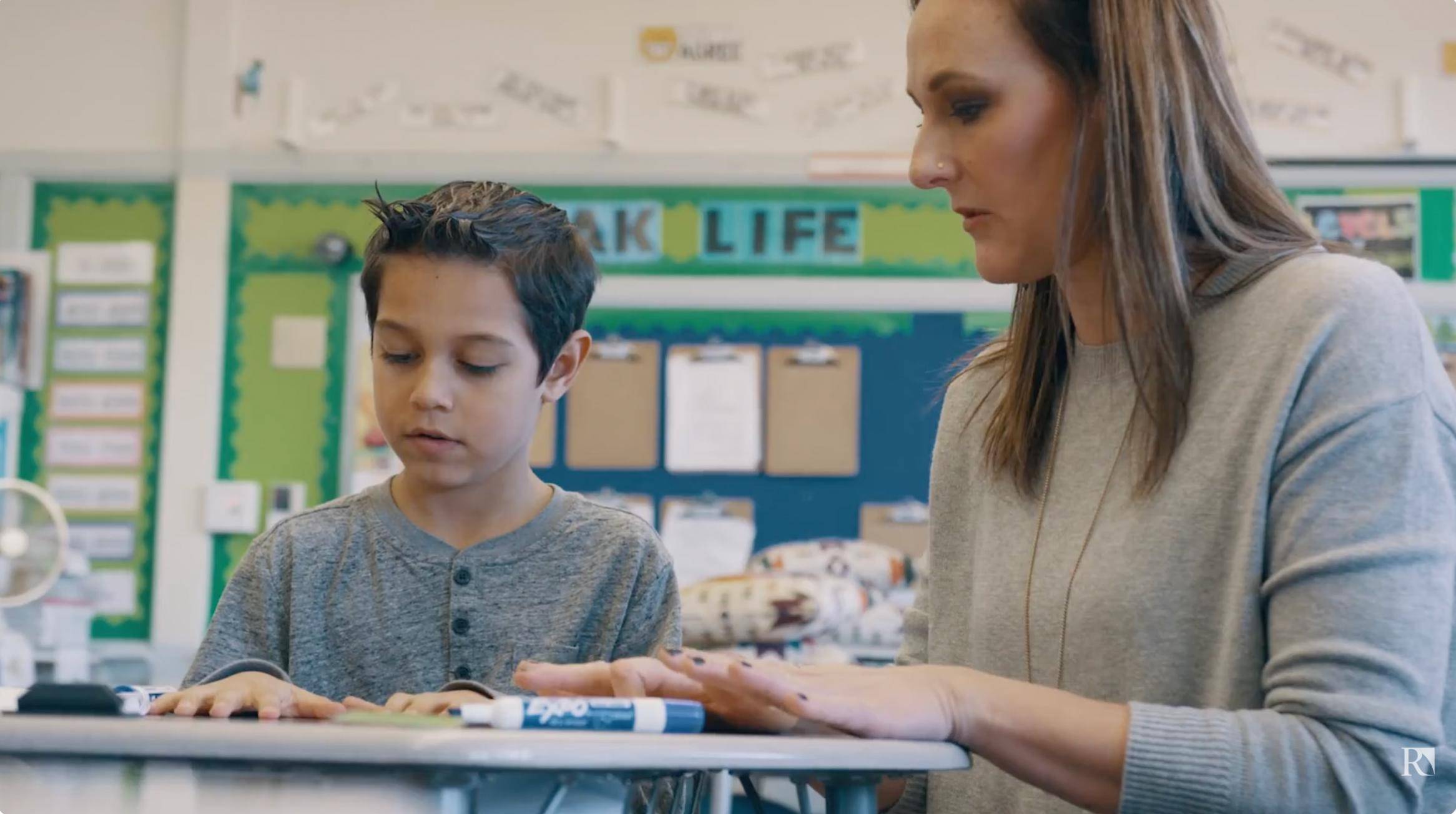 a woman and a boy sitting at a desk