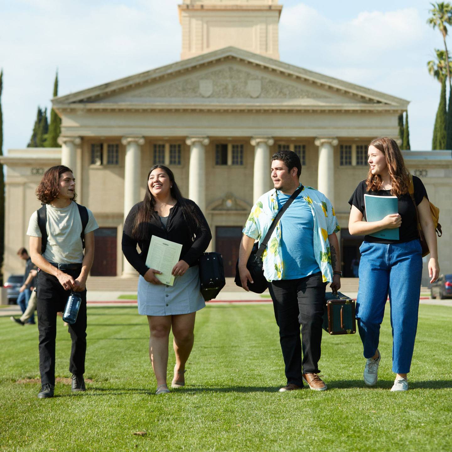 a group of people walking on grass in front of a building