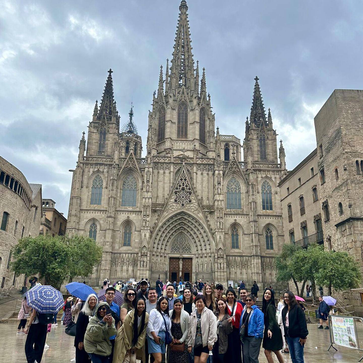 a group of people standing in front of a large stone building with Barcelona Cathedral in the background