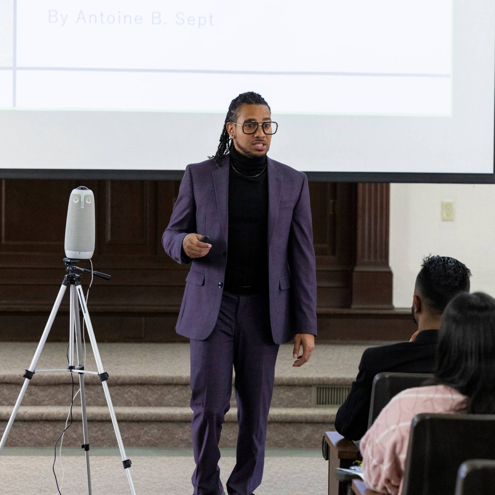 a man in a suit standing in front of a projector screen