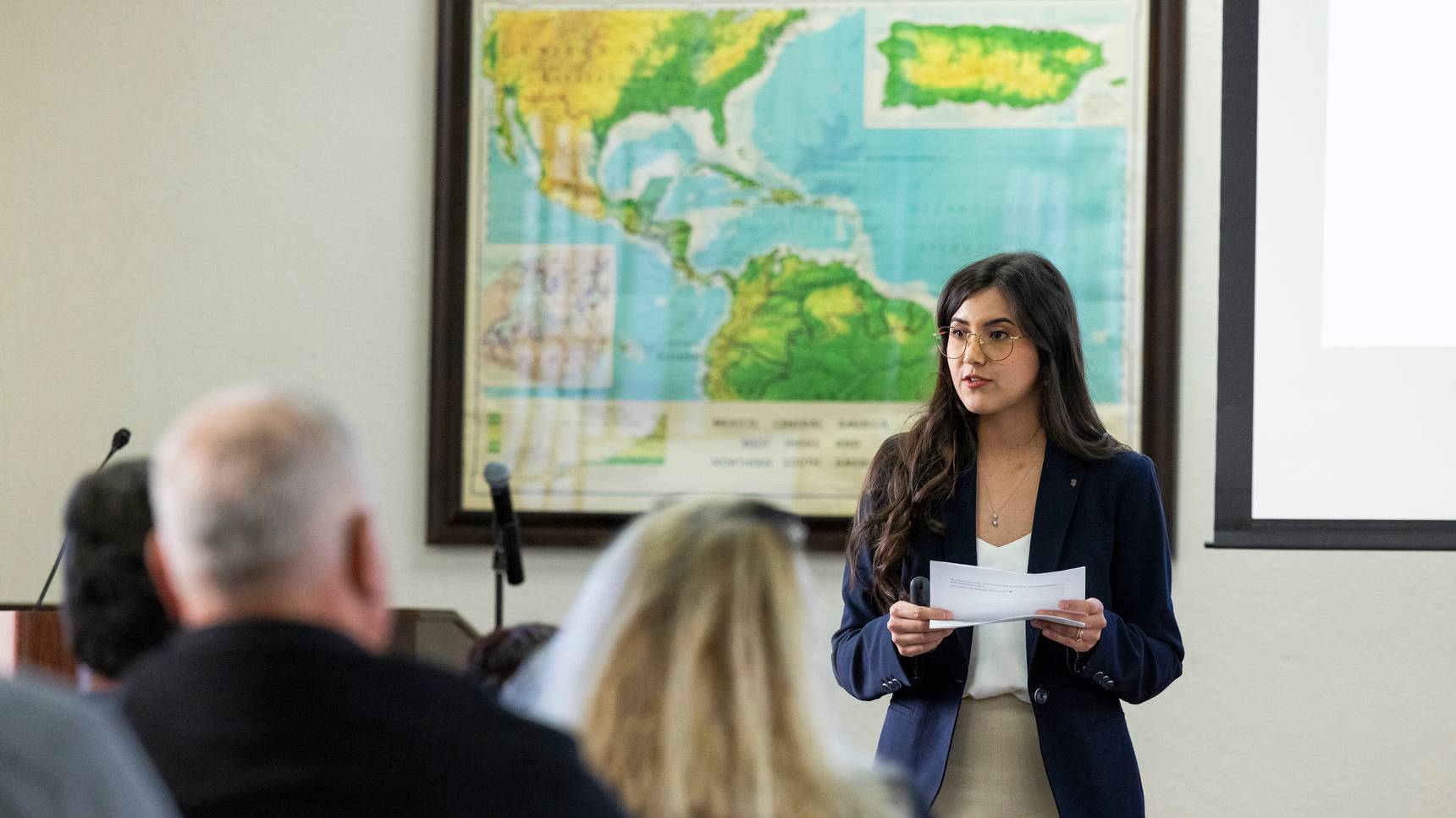 a woman holding a piece of paper in front of a group of people