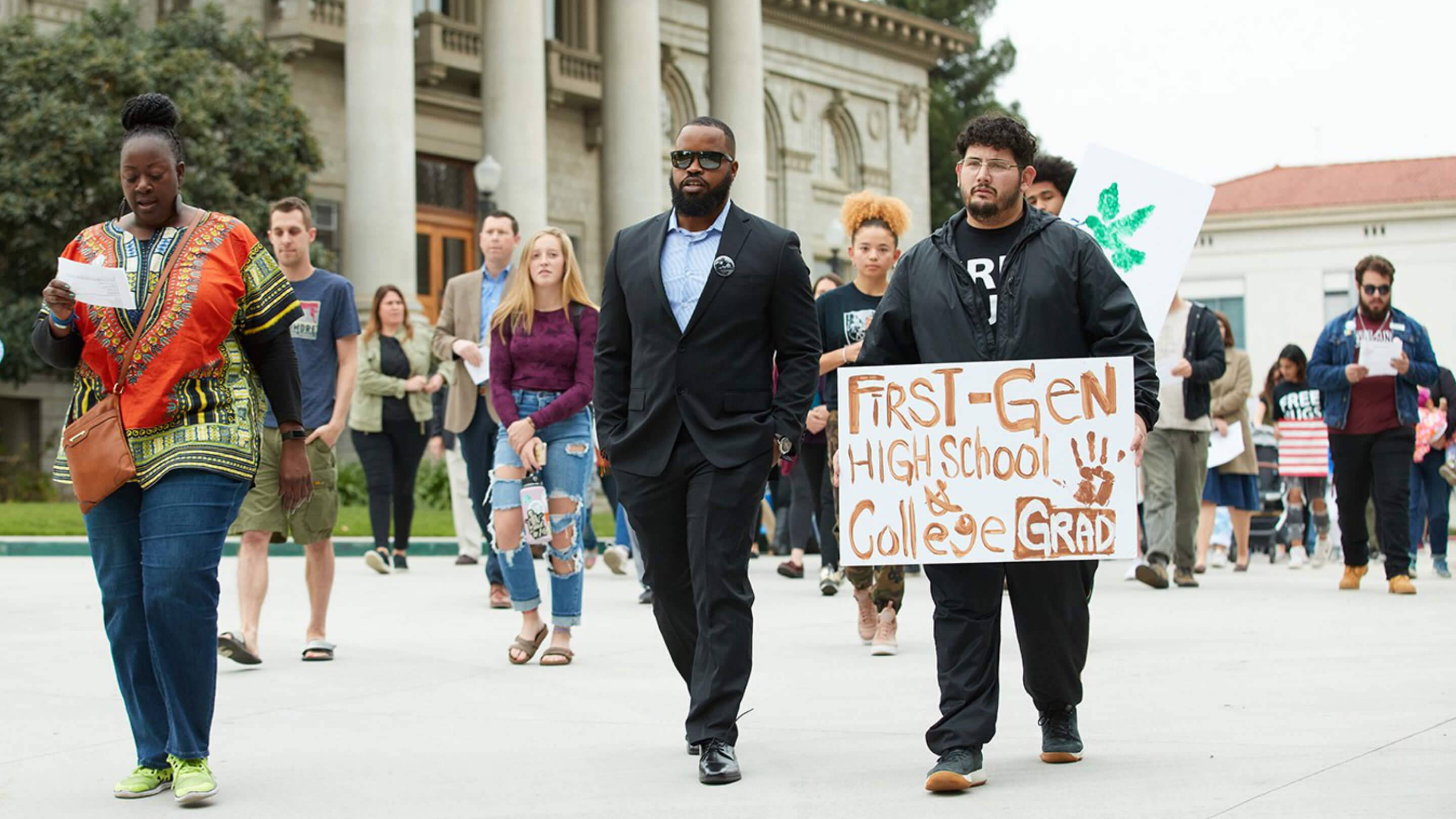 a group of people walking down a sidewalk holding signs
