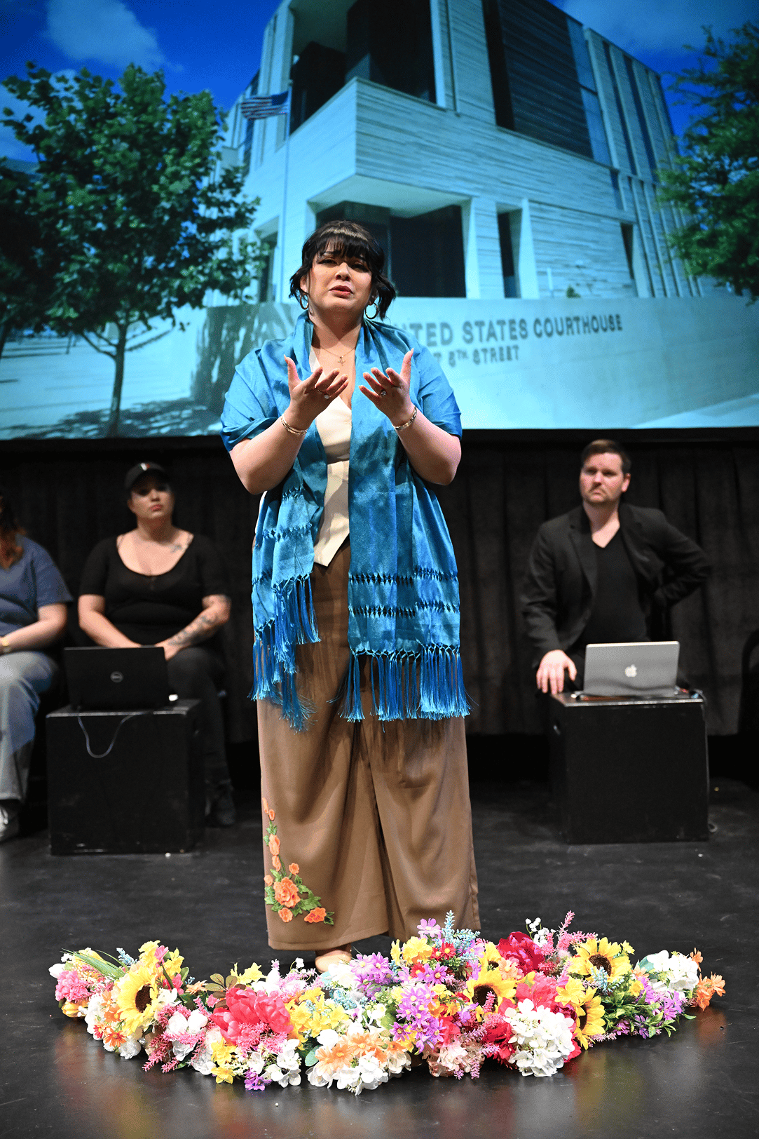 a woman standing on a stage with a group of people behind her