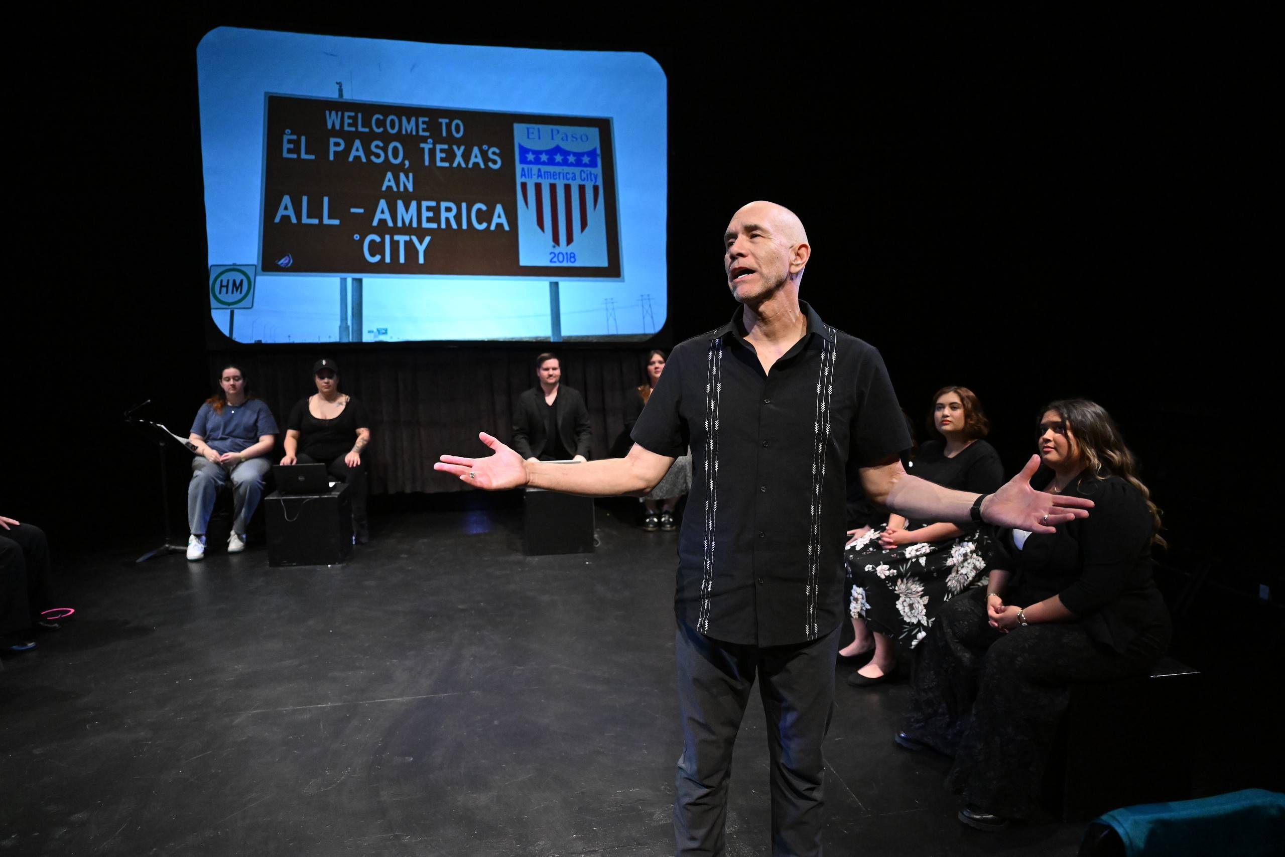 a man standing on a stage with his arms out
