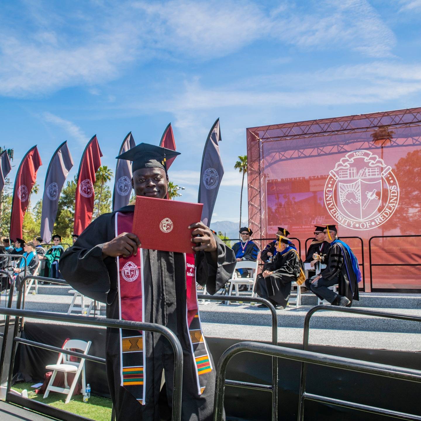 a man in a graduation gown holding a diploma