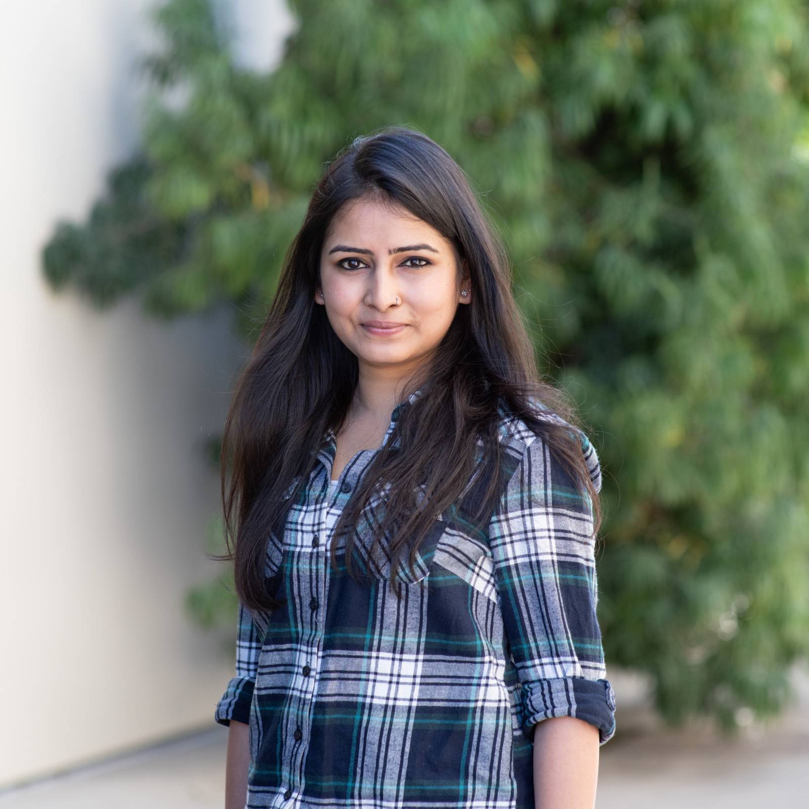 a woman standing outside with trees in the background
