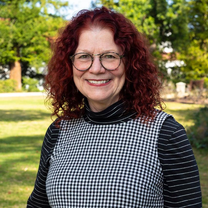 a woman with red curly hair wearing glasses and a black and white checkered shirt