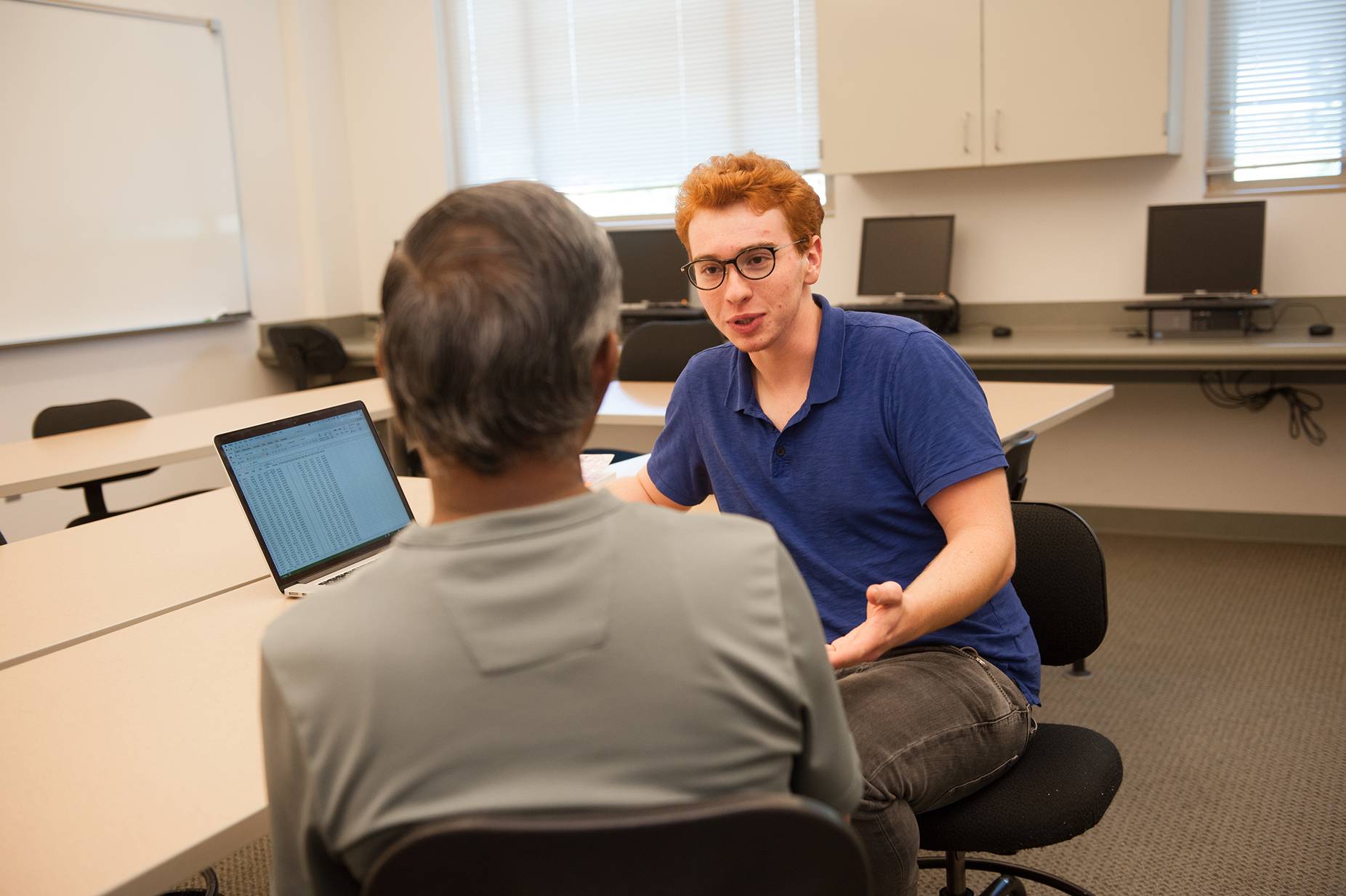 a man sitting in a chair talking to a man