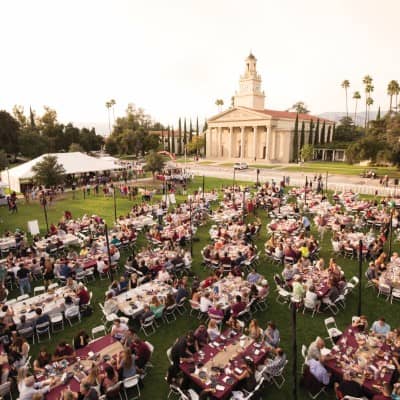 a large group of people sitting at tables in a field