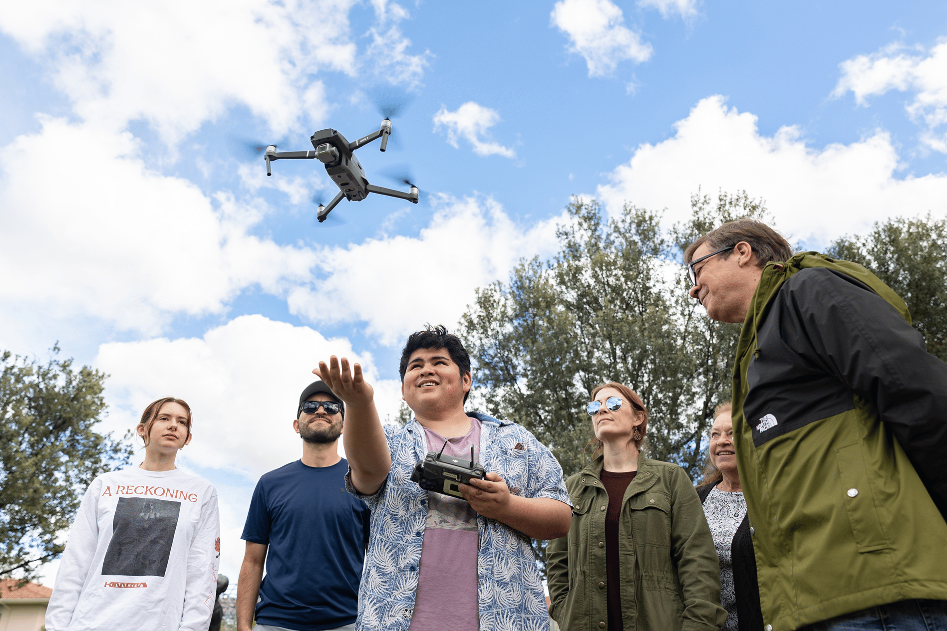 a group of people looking at a drone flying in the sky