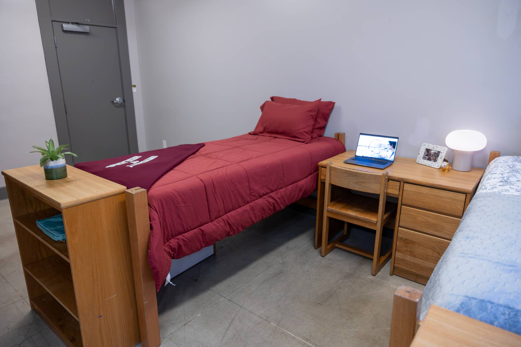 a bed with a laptop on the side of a desk