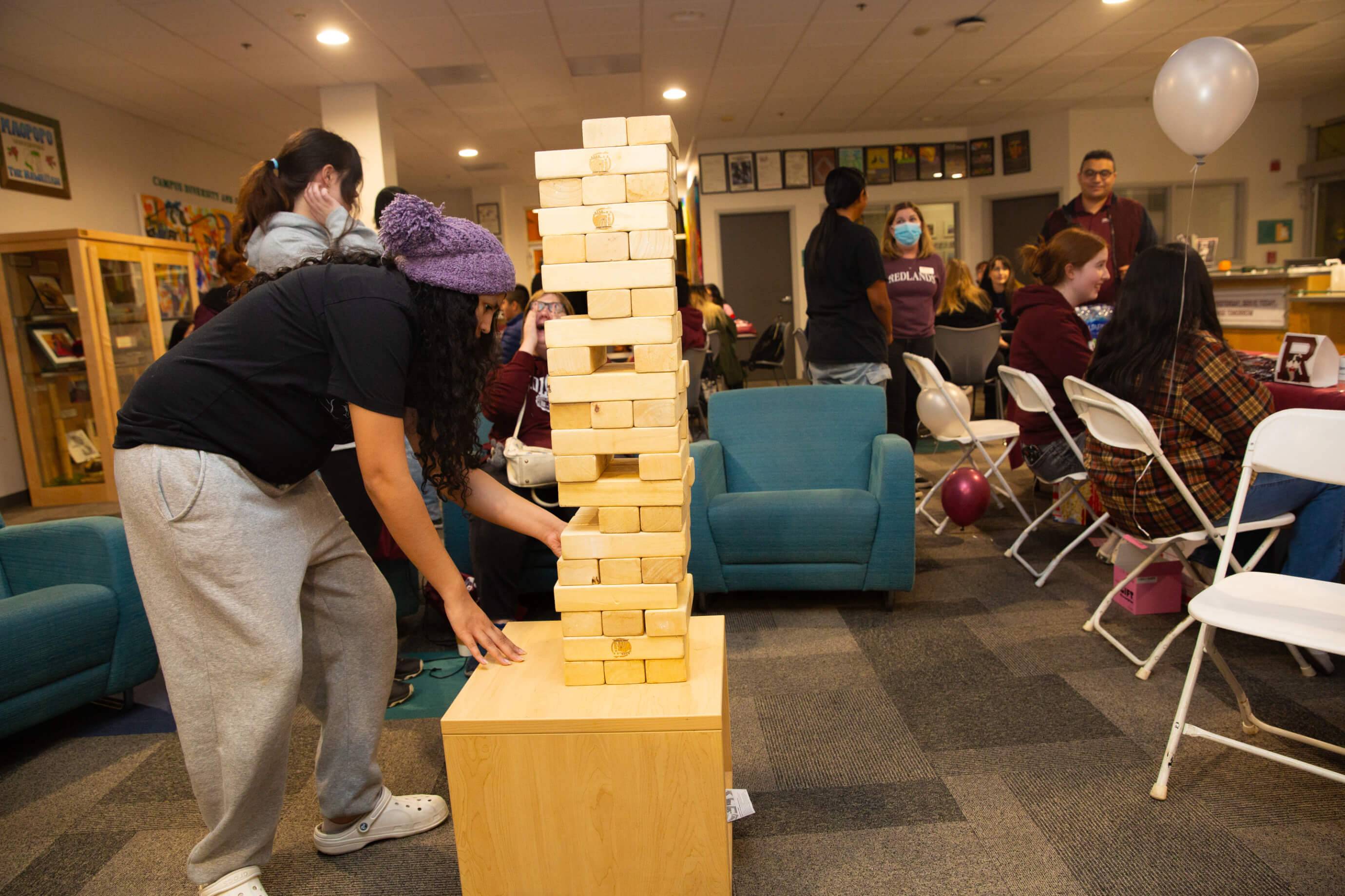 a woman playing jenga in a room with other people