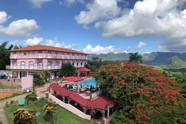a pool and a building with trees and mountains in the background