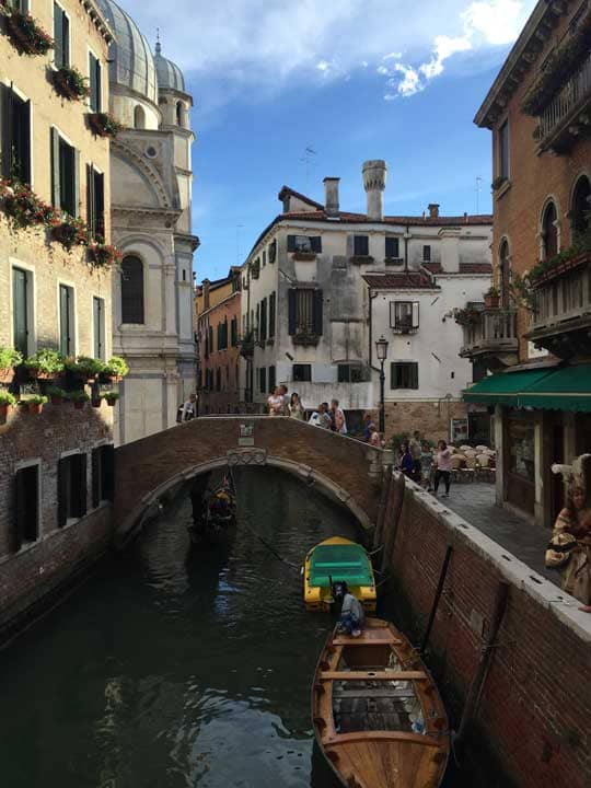 a canal with boats and people walking around