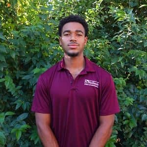 a man standing in front of bushes