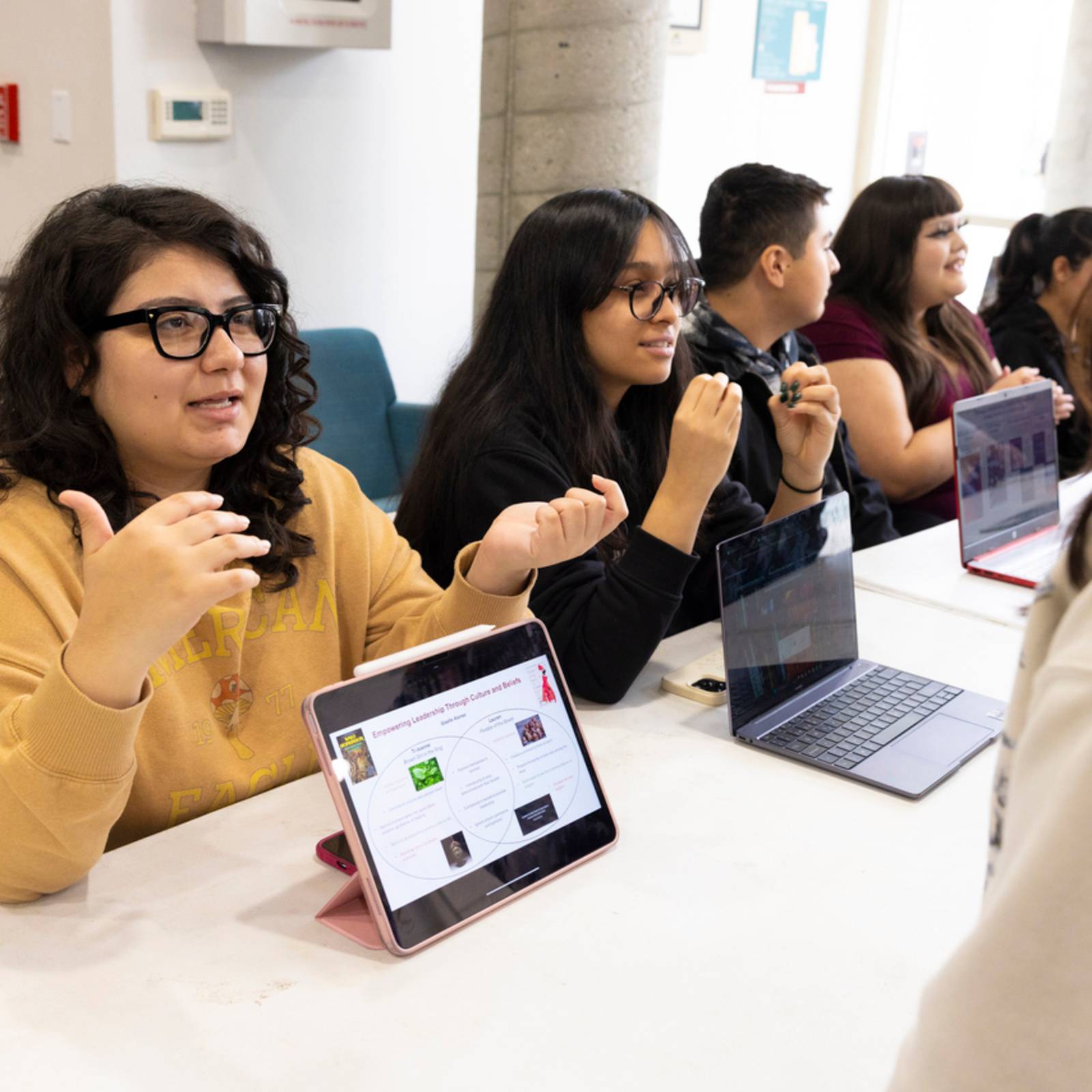 a group of people sitting at a table with laptops
