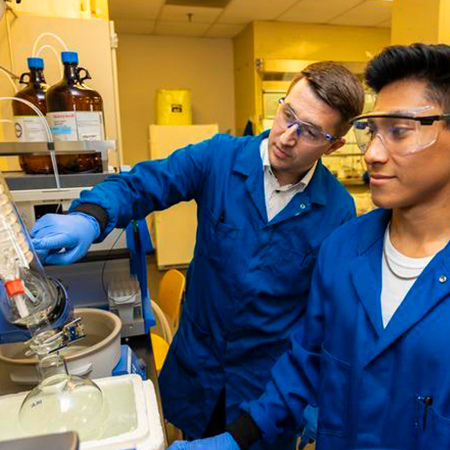 Professor teaching student in research science lab.