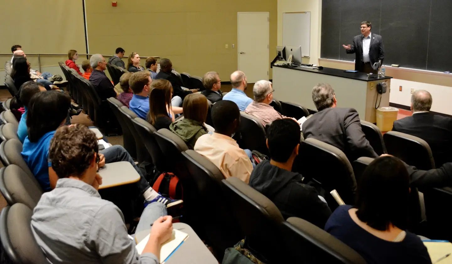 a man standing in front of a group of people in a lecture hall
