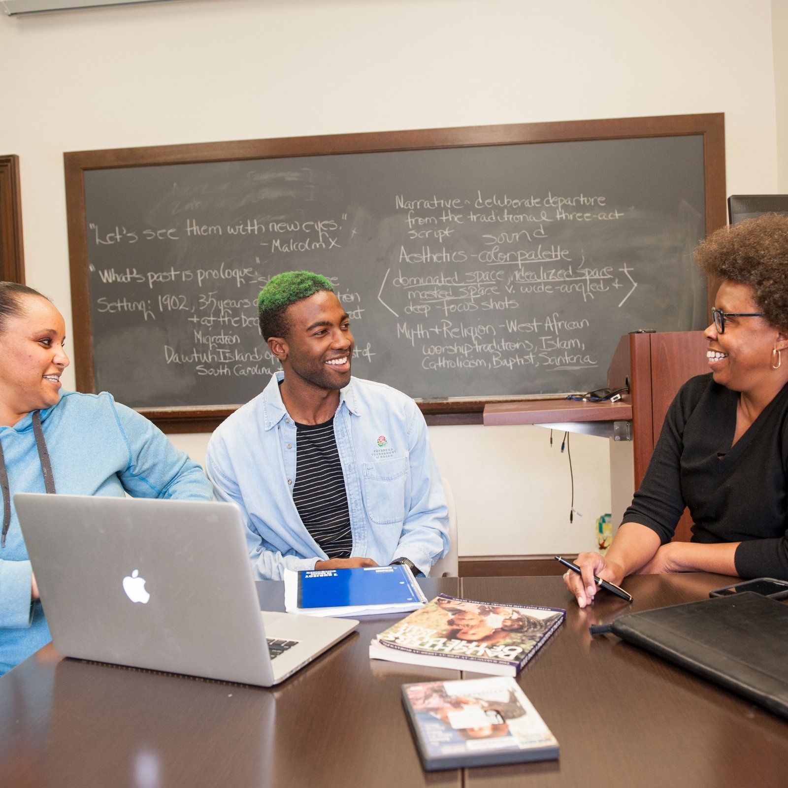 a group of people sitting at a table with laptops