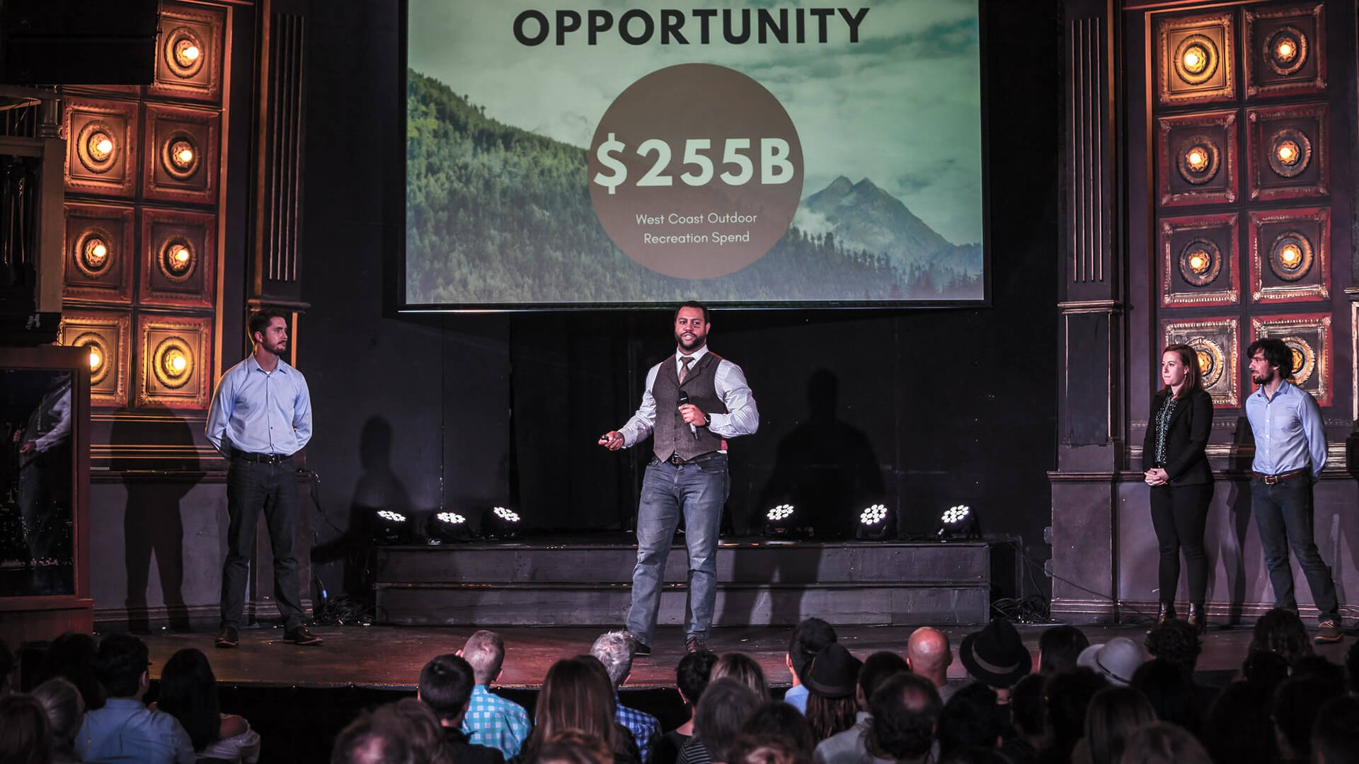 a man on a stage with a large screen and a large crowd