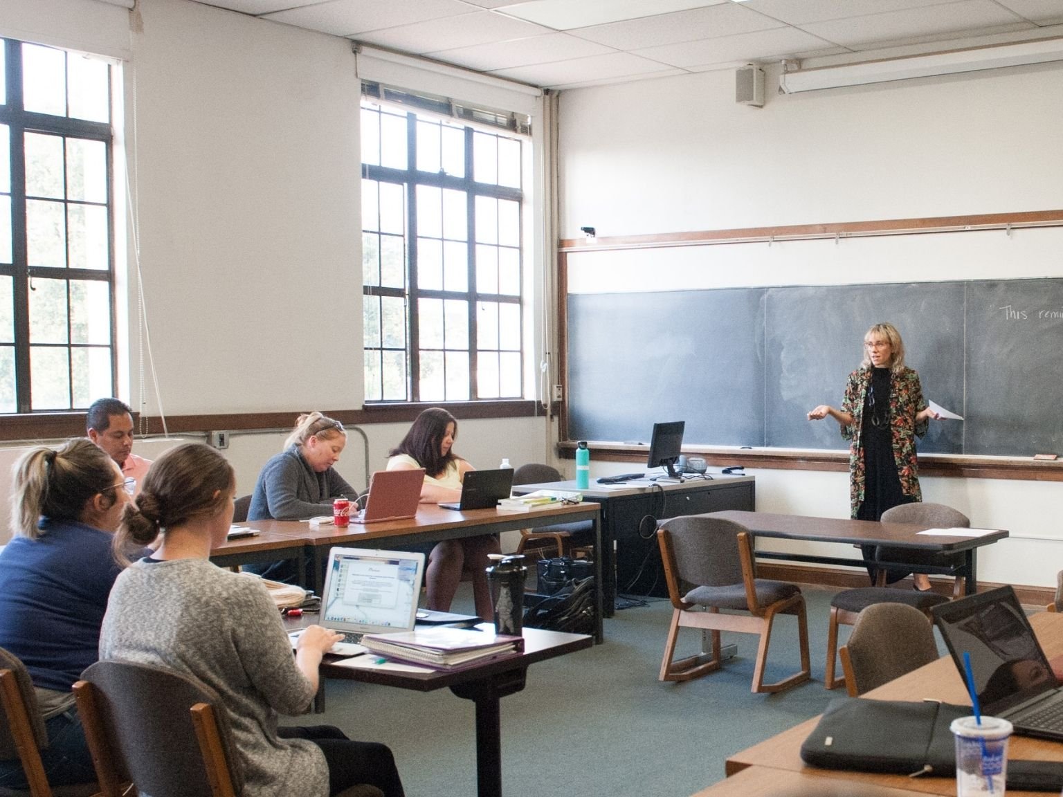 a woman standing in front of a chalkboard in a classroom