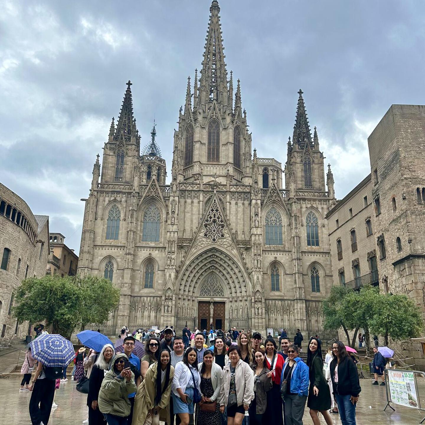 a group of people standing in front of a large stone building with Barcelona Cathedral in the background