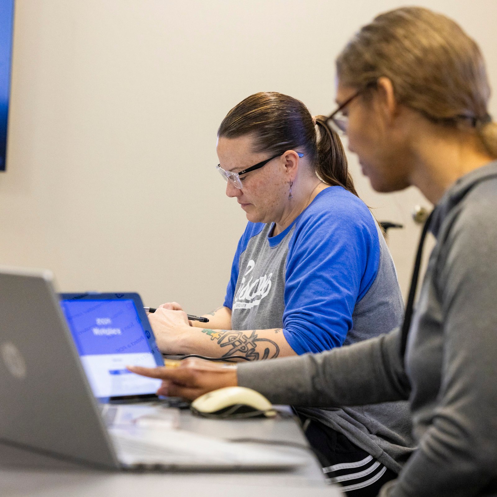 a group of people sitting at a table with laptops
