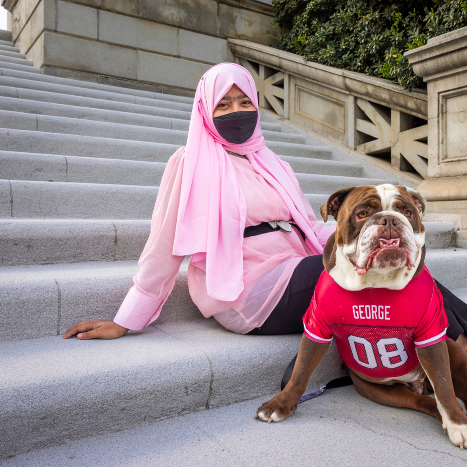 a woman wearing a face mask sitting on stairs with a dog