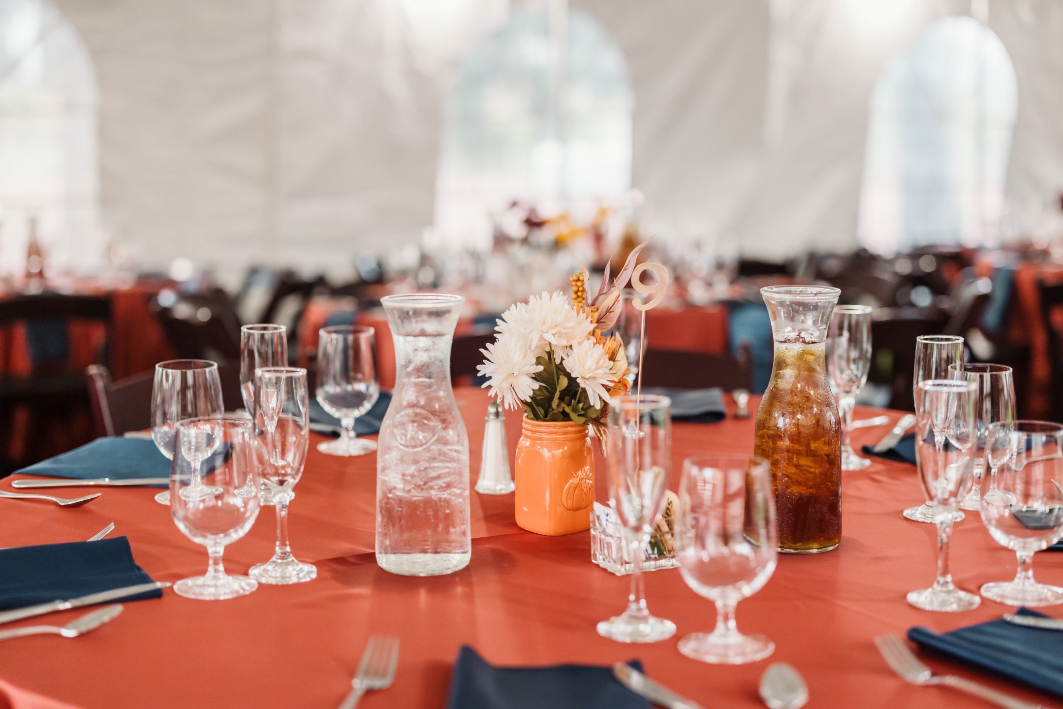 a table set with glasses and vases of flowers