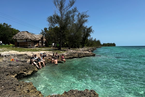 a group of people sitting on rocks by the water