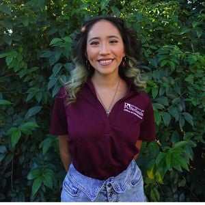 a woman smiling in front of a bush