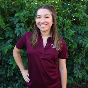 a woman standing in front of a bush