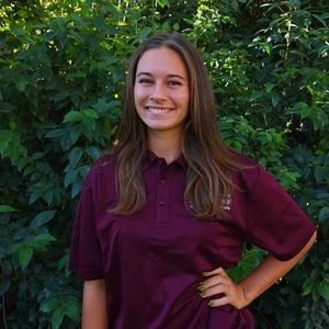 a woman smiling in front of bushes