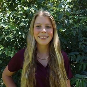 a woman smiling in front of a bush