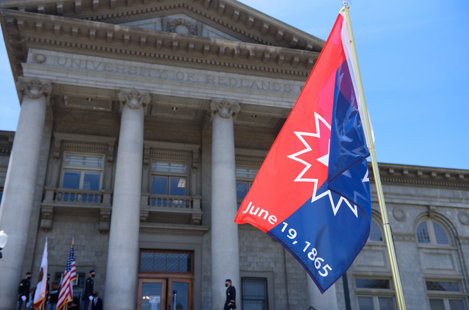 The Juneteenth flag stands on a pole in front of the Administration Building at the Redlands campus