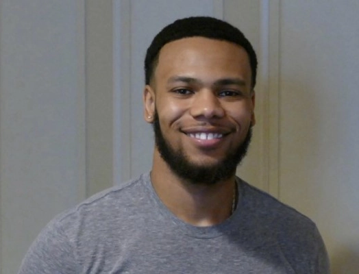 Jacob Green, in a gray T-shirt, smiles at the camera while standing indoors.
